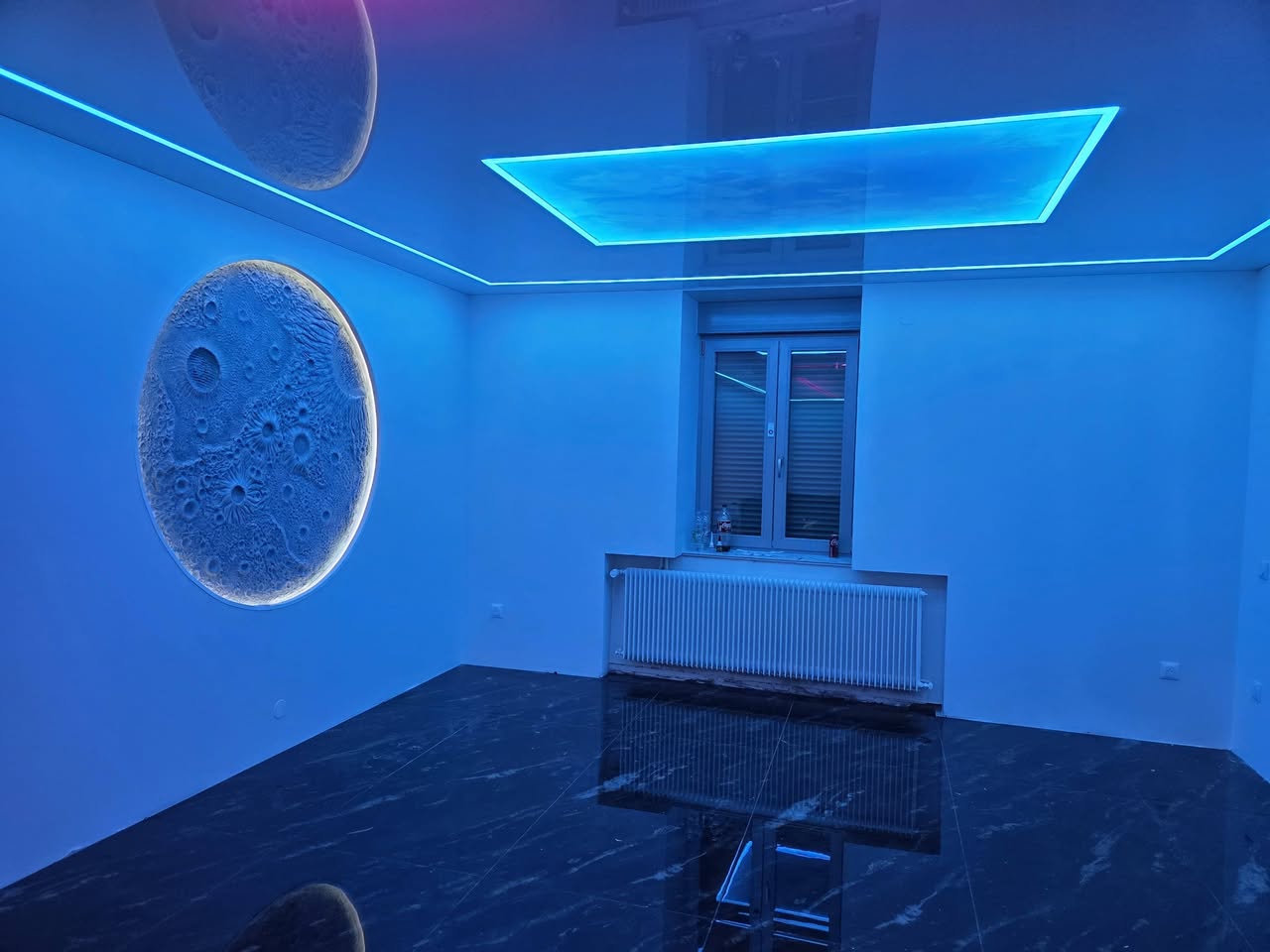 Intérieur rénové avec décor mural lunaire en relief et éclairage bleu